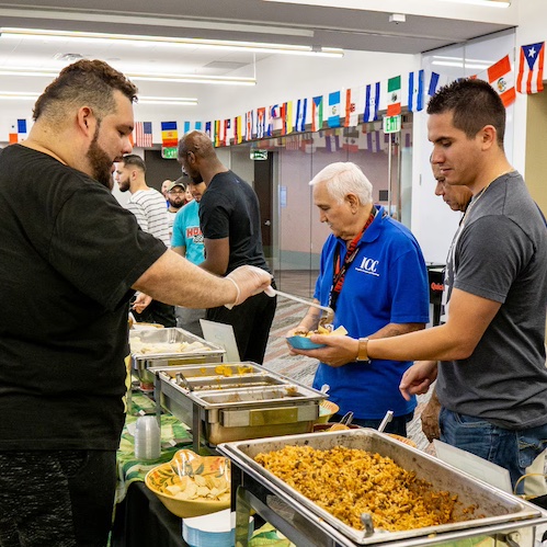 Group of people around an international lunch buffet.